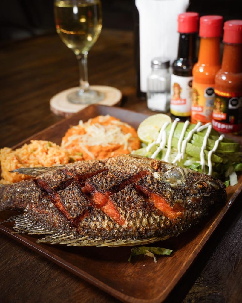 Whole fried fish with rice, refried beans, avocado, and lime, served with hot sauces and wine.
